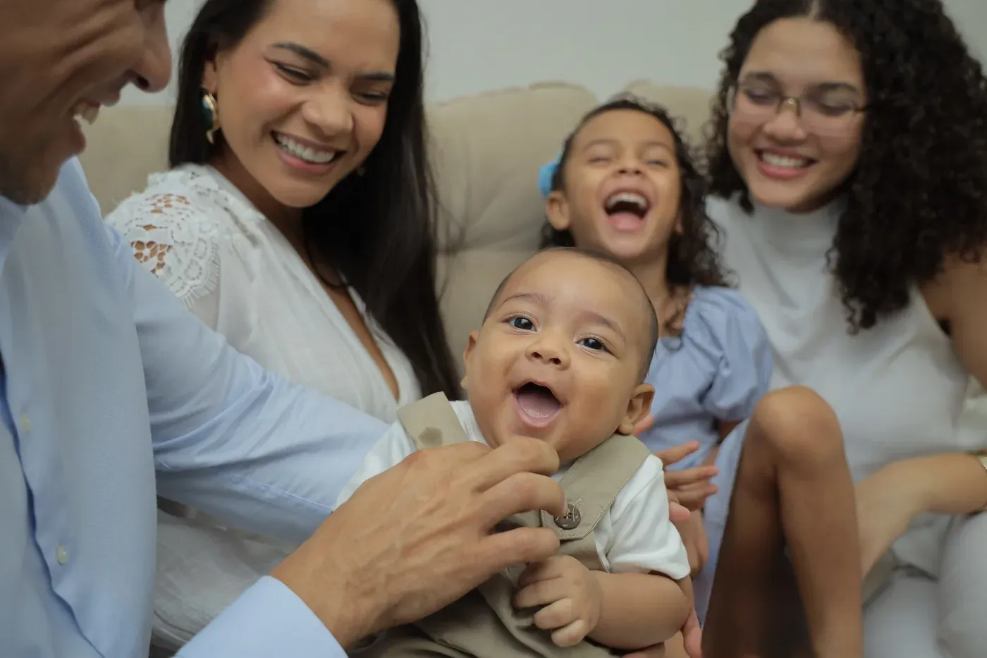 Família reunida, sorrindo e celebrando com o bebê recém-chegado no colo